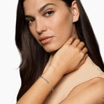 Woman with long dark hair touching her neck against a white background featuring an Open cable bracelet with two blue colors gemstones and mixed metal end caps. 