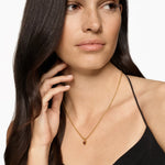 Red Gemstone Heart Necklace on a Gold Chain on a Brunette Model. 