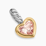 Heart-shaped enhancer with pink gemstone and gold and silver accents on a white background