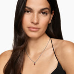Woman wearing a garnet amulet necklace with a white background