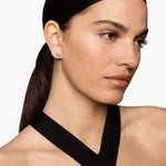 up close shot of a woman wearing a silver earring with a diamond in the center 